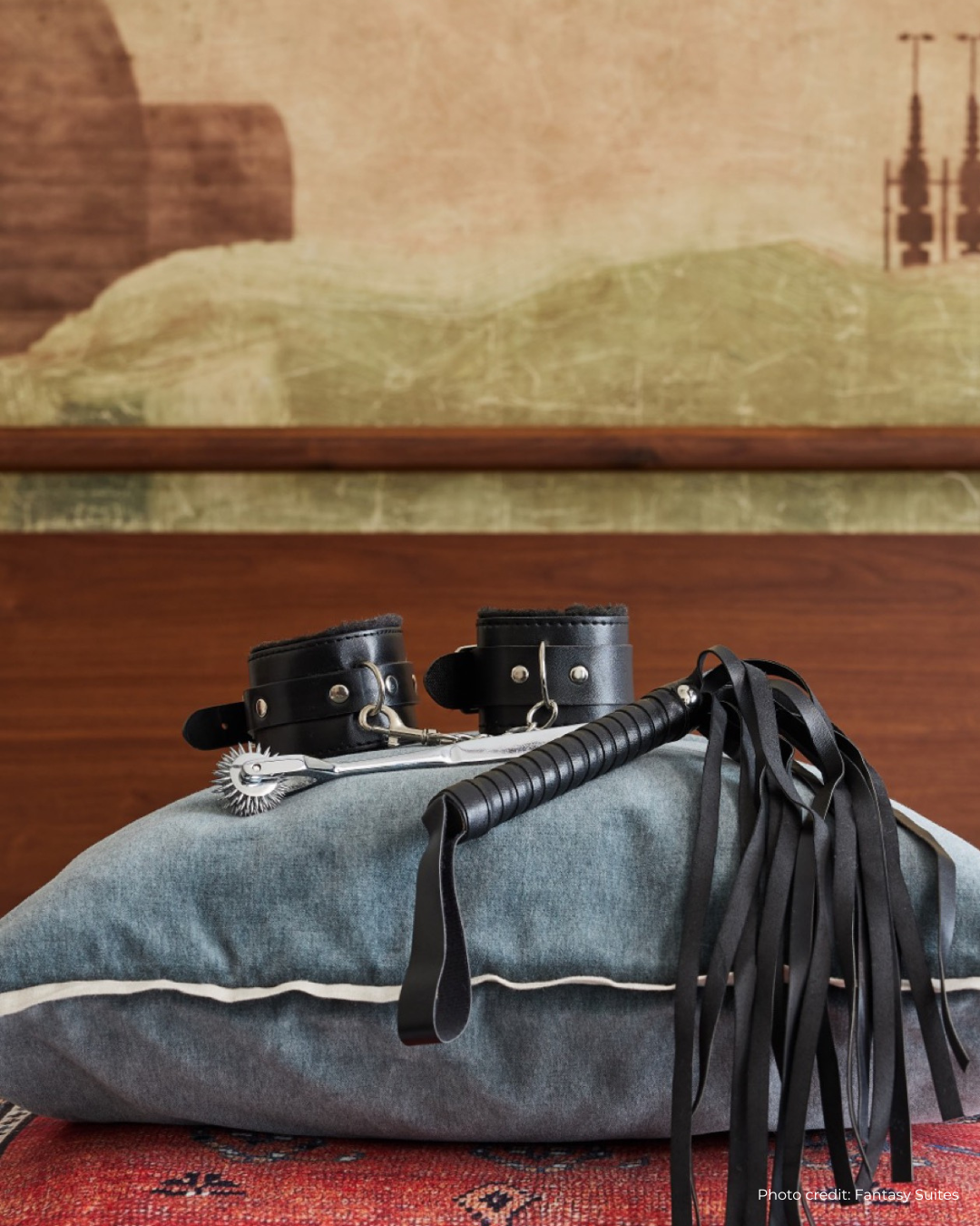 Black leather restraints and a whip on a textured pillow with a blurred background